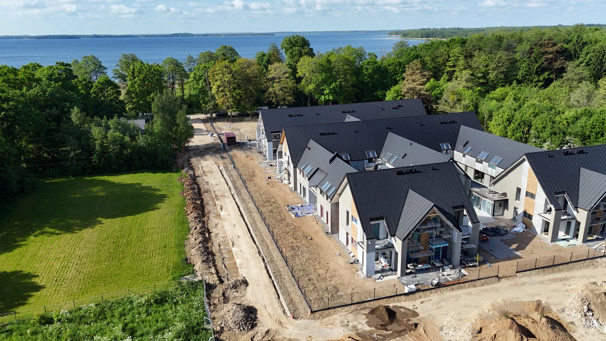 Boczne ujęcie kompleksu Yacht Apartment z widoczną zabudową i jeziorem w tle