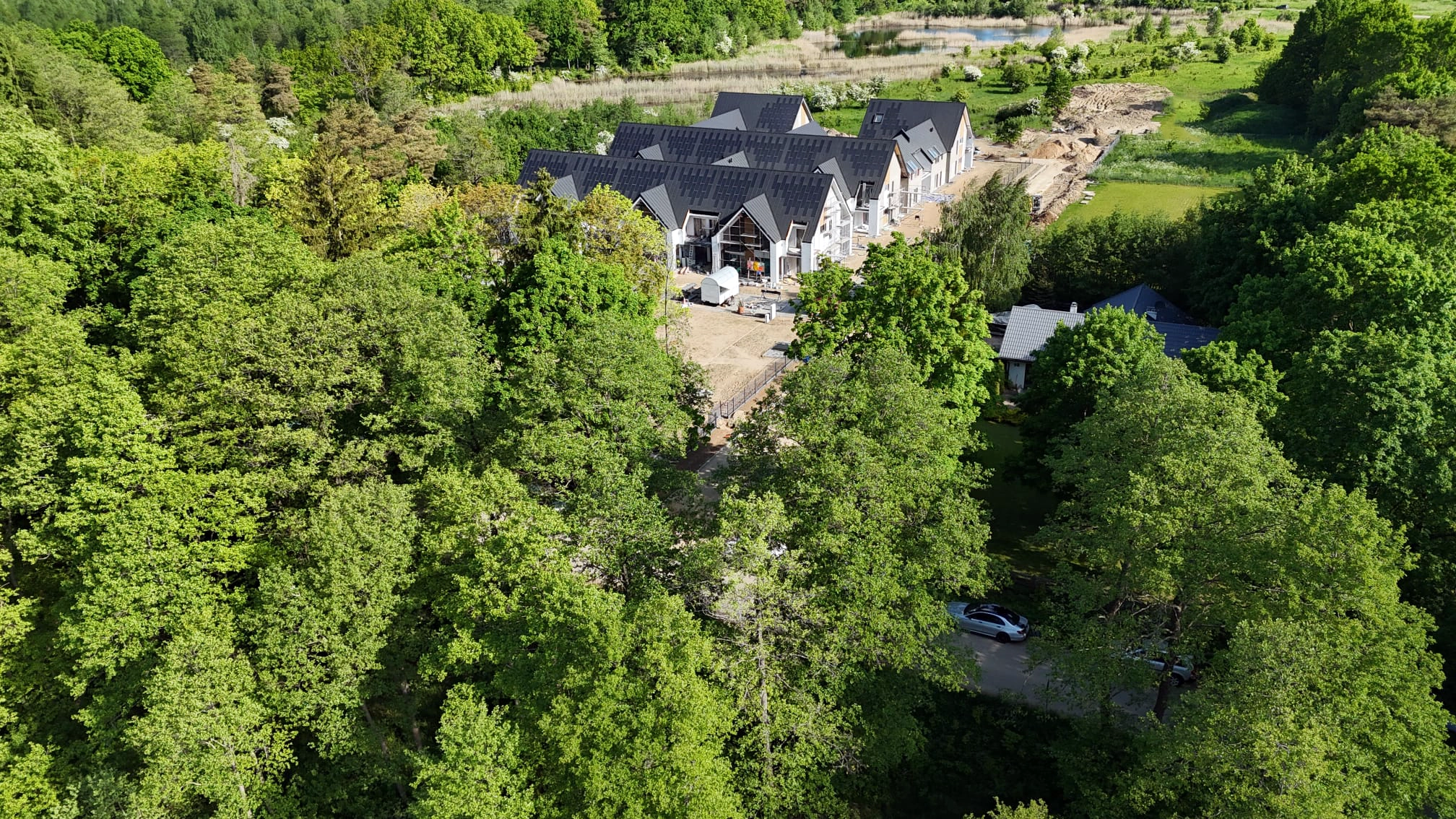 Widok z drona na linię brzegową jeziora oraz zielone tereny wokół Yacht Apartment