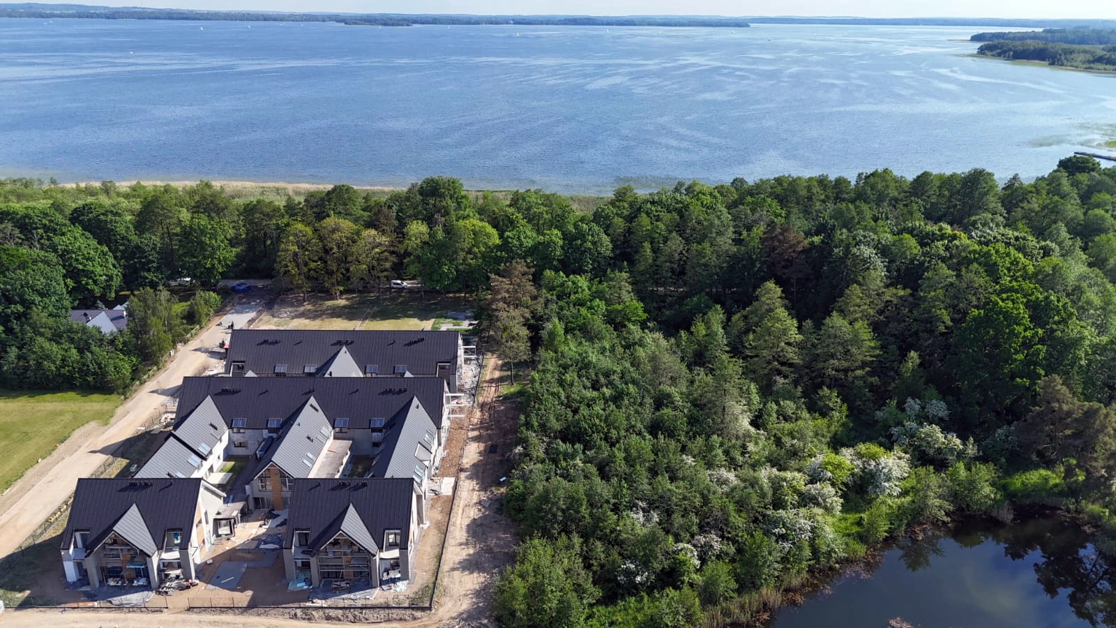 Szerokie ujęcie z drona kompleksu Yacht Apartment w sąsiedztwie jeziora i zieleni