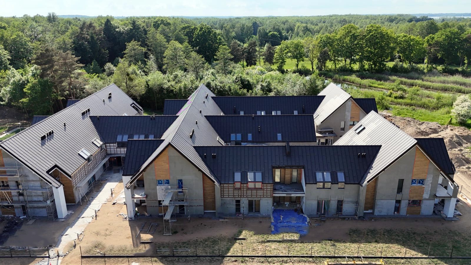 Budynki Yacht Apartment widziane z drona w otoczeniu zieleni i przy linii brzegowej