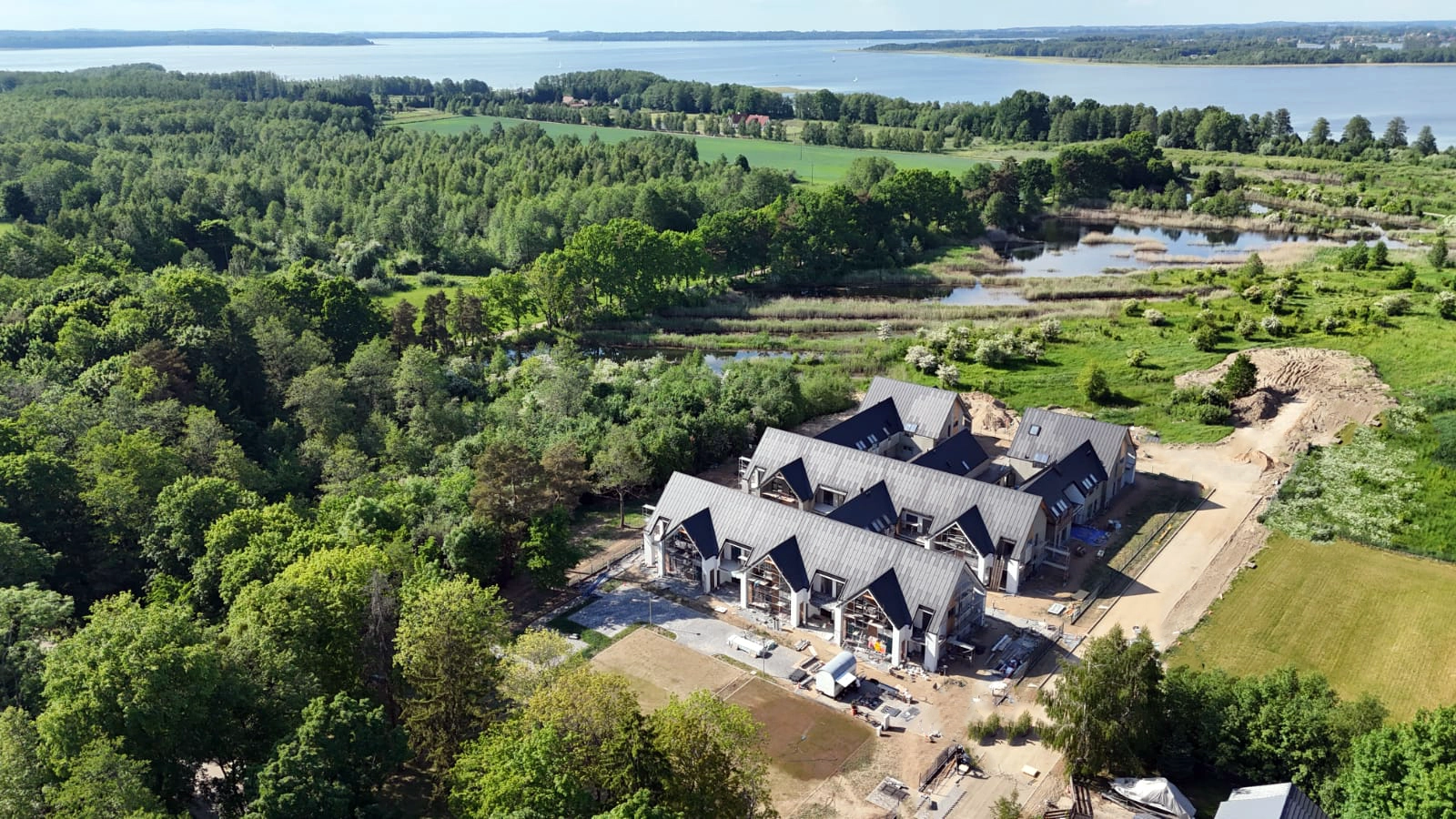 Yacht Apartment otoczony lasem, terenami zielonymi i jeziorem widziany z drona