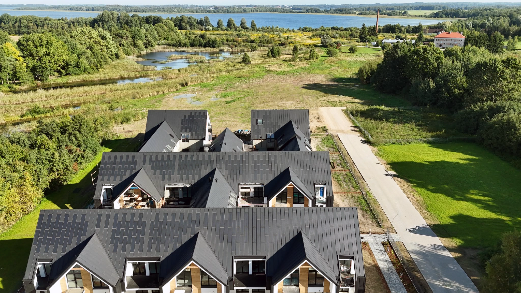 Boczna elewacja Yacht Apartment z drewnianymi detalami, alejką i terenem wokół budynków