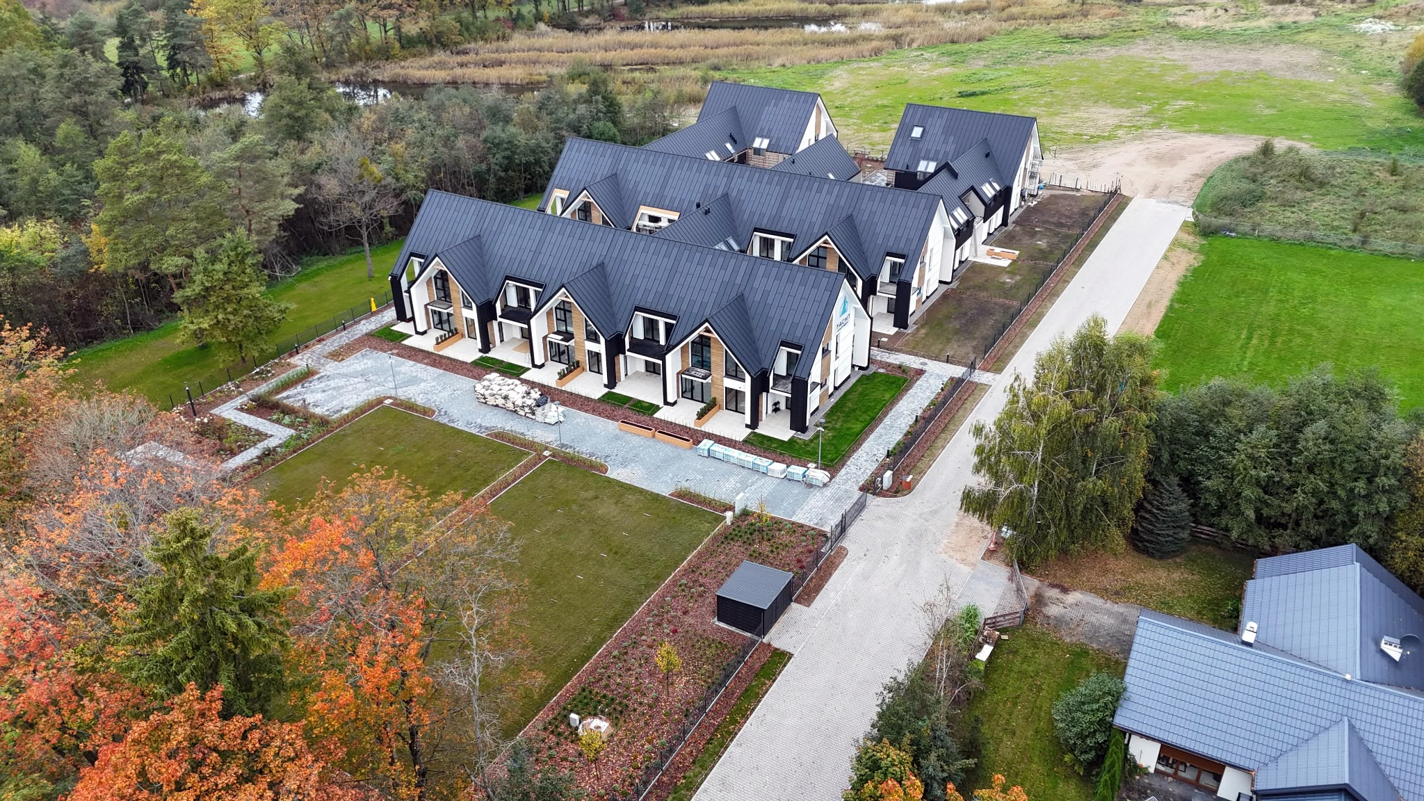 Front budynków Yacht Apartment widziany z drona z lasem i zielonym terenem wokół kompleksu