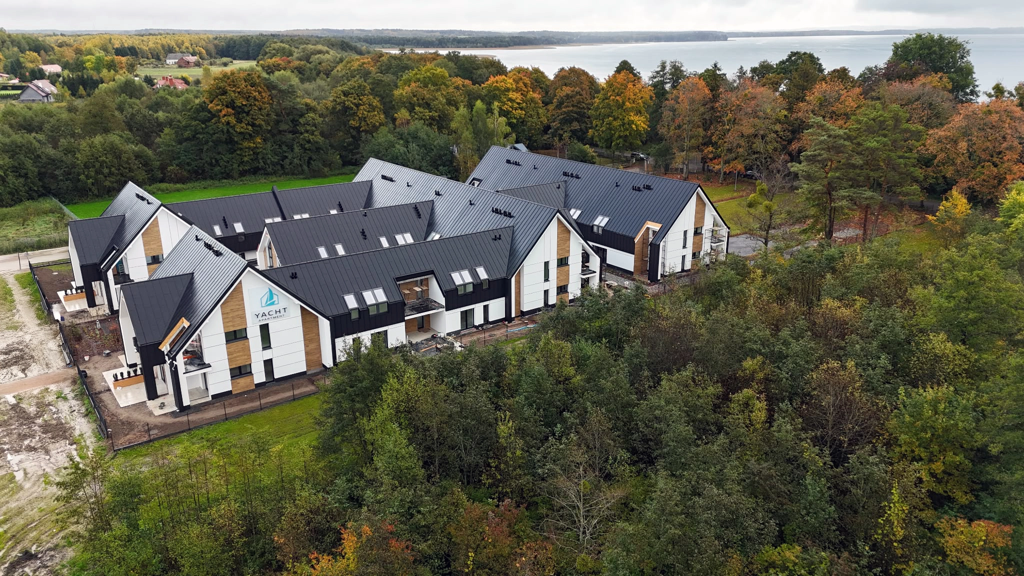 Elewacja Yacht Apartment z logo marki, drewnianymi akcentami i przejściem pomiędzy budynkami