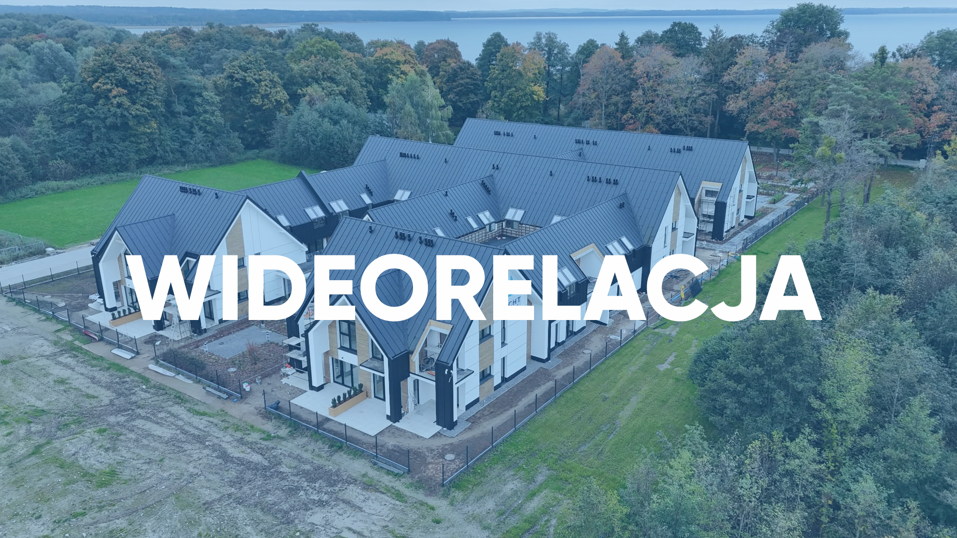 Widok z drona na kompleks Yacht Apartment z grafitowymi dachami, jasnymi elewacjami i jesiennym lasem w tle